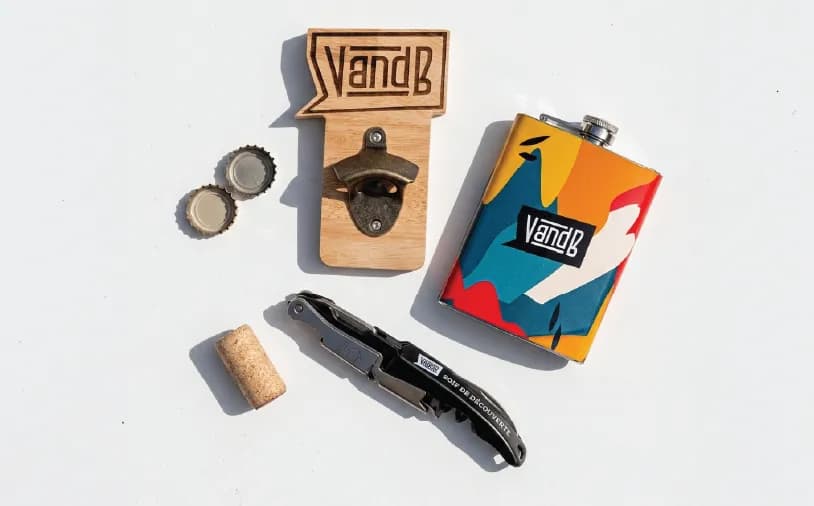 VandB branded bottle opener, colorful flask, and corkscrew neatly arranged on a white surface.