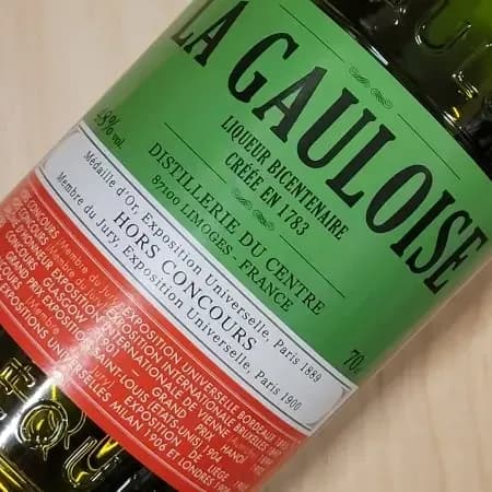 Close-up of a green bottle of La Gauloise liqueur with a prominent green and red label.