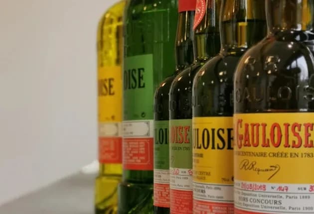 Row of vintage green and yellow glass bottles with 'Gauloise' labels on a white background.