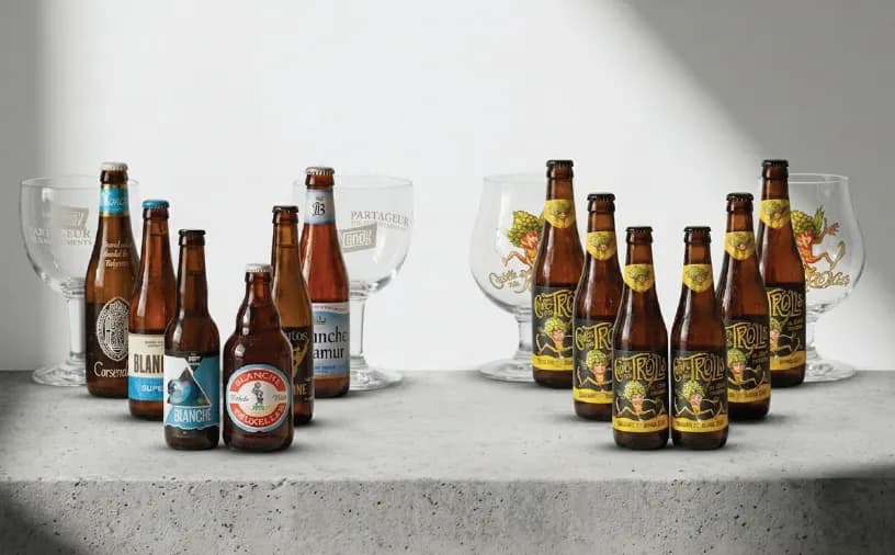 Assortment of beer bottles and glasses arranged on a light surface.