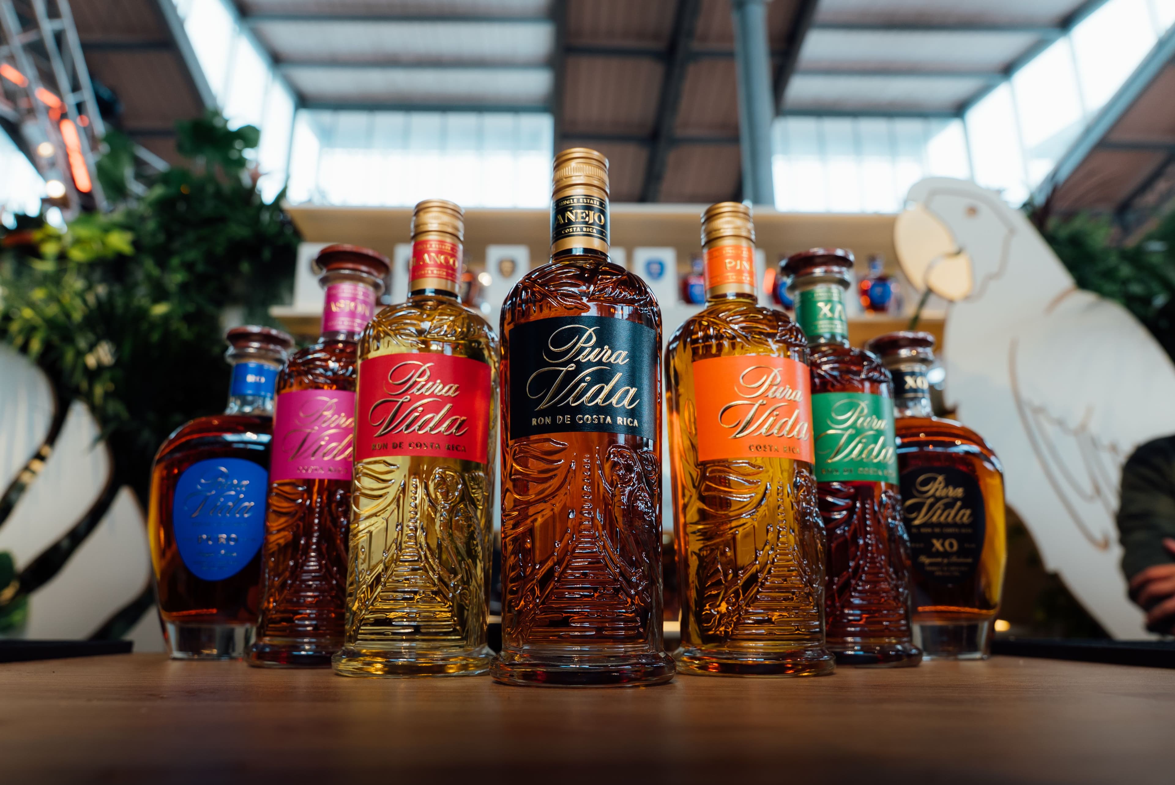 A collection of Pura Vida spirit bottles with colorful labels arranged on a wooden table.