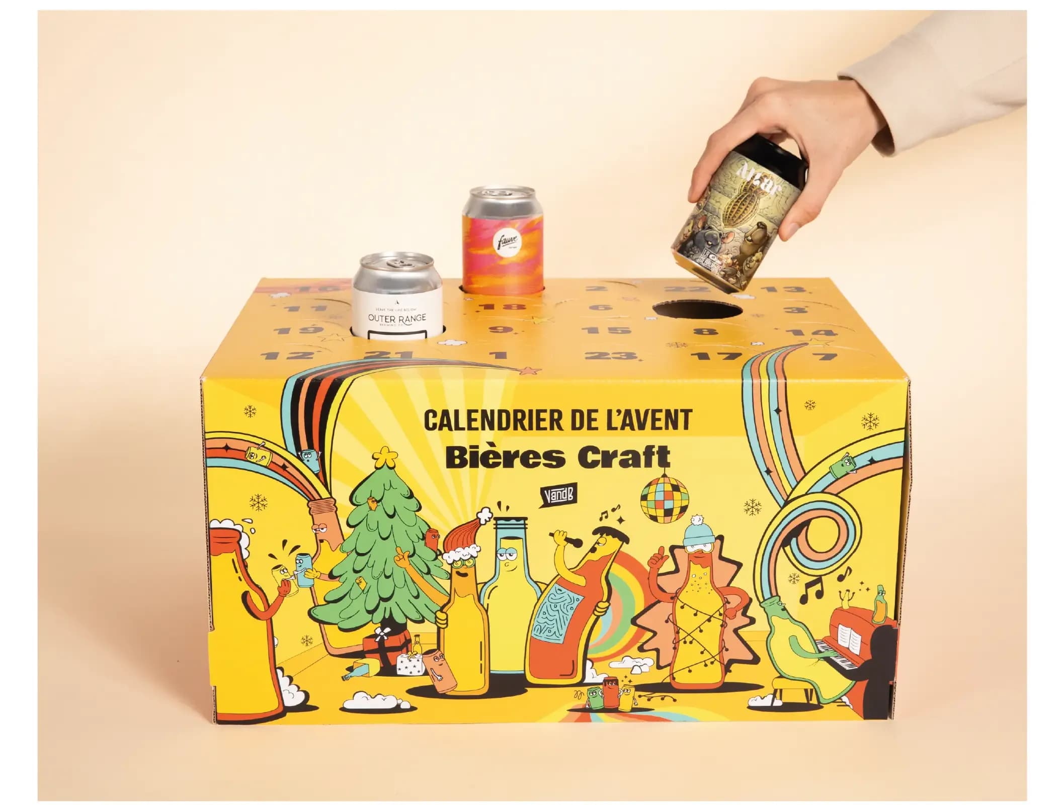 Hand places a craft beer can into a festive yellow Advent calendar box.