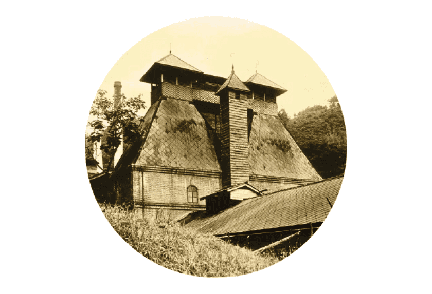 Sepia-toned historical wooden building with two distinctive pointed towers and traditional architecture.
