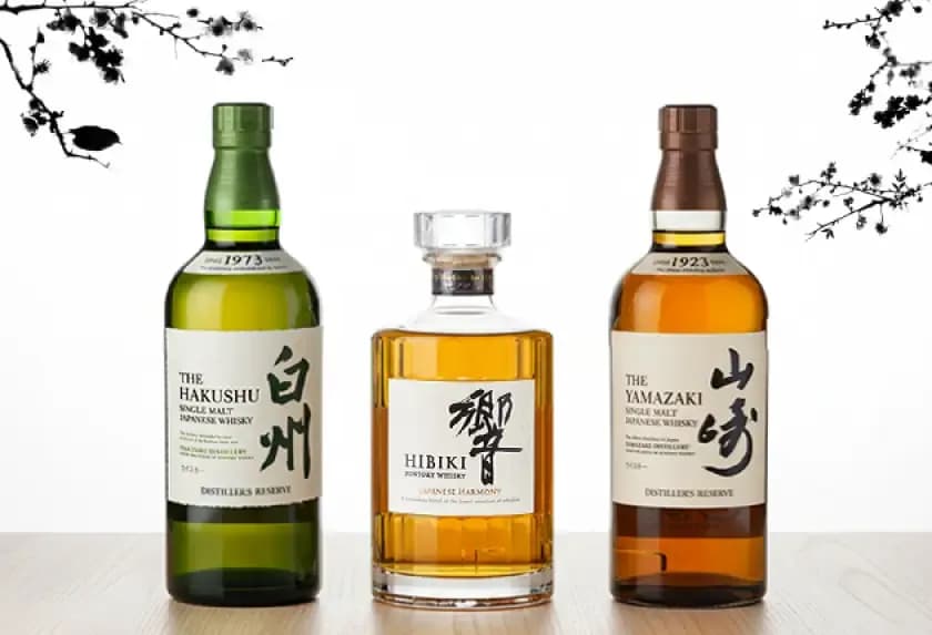 Three distinct Japanese whisky bottles: Hakushu, Hibiki, and Yamazaki, on a white background.